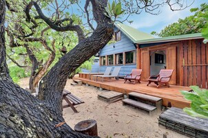 A wooden deck with lounge chairs, a building with a green roof, and a large tree.