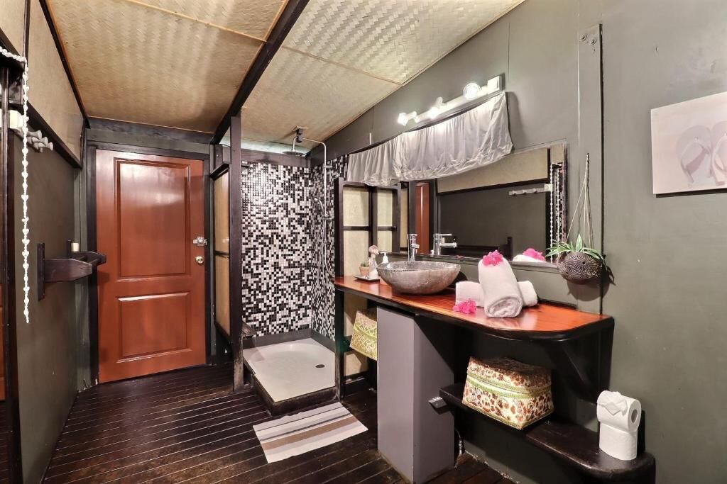 A bathroom with a wooden door, a patterned wall, a sink with a large bowl, a mirror, and towels.