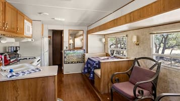 A compact kitchen with wooden cabinets, a sink, a stove, and a window with a view of trees.