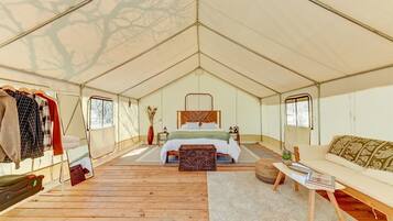 Een tent met een bed, een kledingrek, een klein tafeltje en een bank.