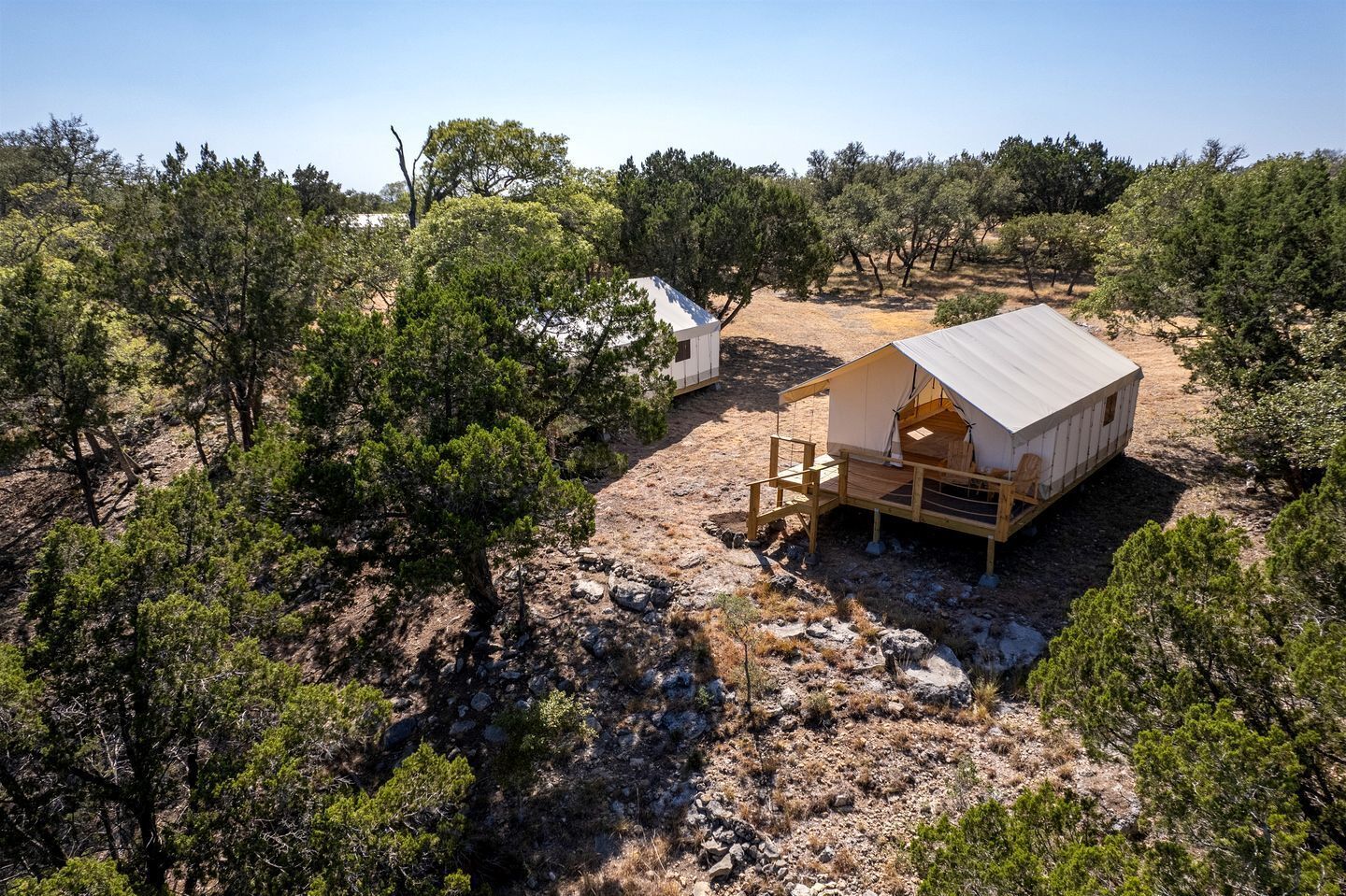 A rustic outdoor accommodation with a wooden deck and a tent-like structure.