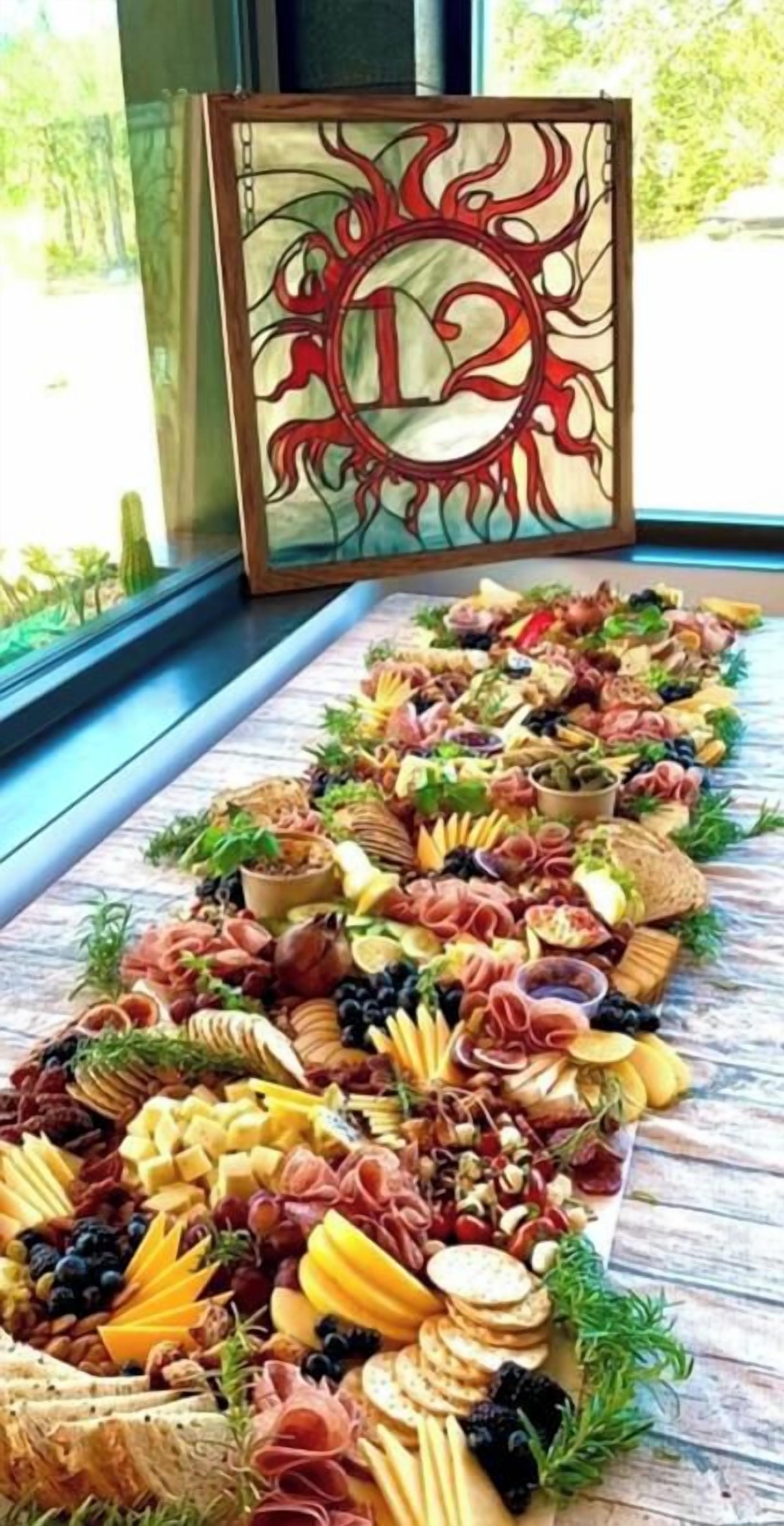 Uma tábua de frios com diversos queijos, carnes e frutas sobre uma mesa de madeira.