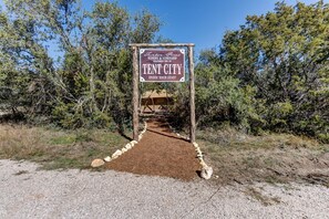 A sign for Tent City, a winery and vineyard, with a dirt path leading to a tent structure. - Safari Tent for Two for Romantic Weekends Away at a Working Winery near Fredericksburg, Texas (Johnson City)