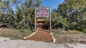 A sign for Tent City, a winery and vineyard, with a dirt path leading to a tent structure.