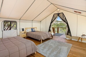 Un hébergement sous tente comprenant deux lits, une petite table et un balcon avec vue.