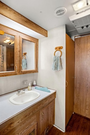 Une salle de bain avec un meuble-lavabo en bois, un miroir, un lavabo et un porte-serviettes.