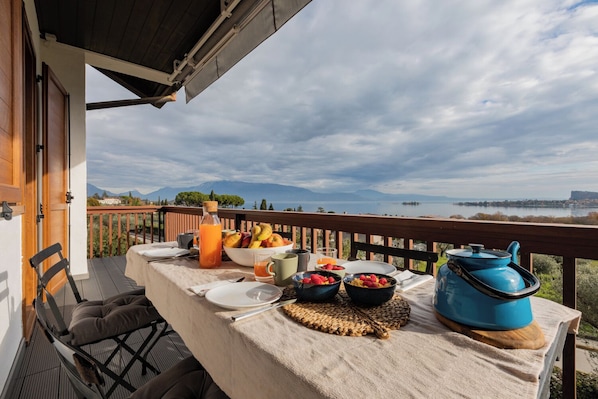 A balcony with a table set for breakfast, including fruits, a beverage, and a teapot. - CASA CATULLO, Paradise Children Apartment in Resort (Lombardia)