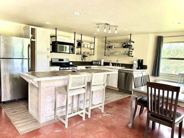 A modern kitchen with a central island, stainless steel appliances, and a dining area with a window view.