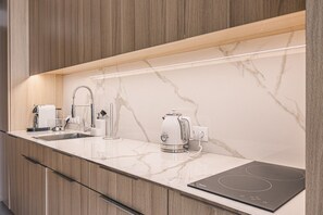 Eine moderne Küche mit Marmorarbeitsplatte, einem eingebauten Backofen, einem Wasserkocher und einer Kaffeemaschine.