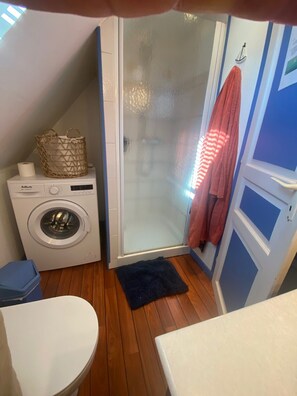 Ein kleiner, kompakter Raum mit Waschmaschine, Dusche und Waschbecken.