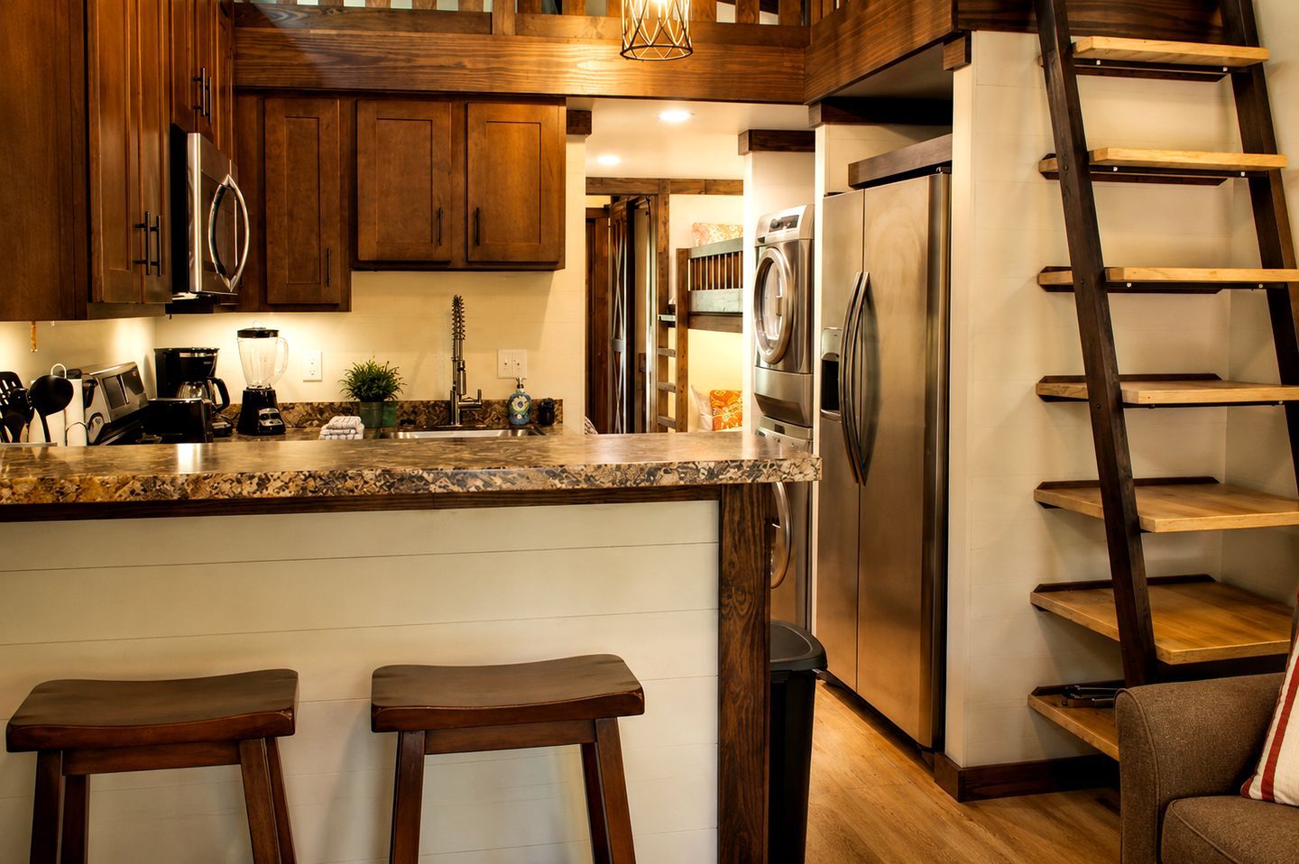 Una cocina con armarios de madera, electrodomésticos de acero inoxidable, encimera de granito y estantería tipo escalera.