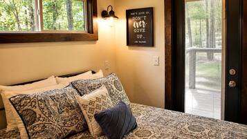 A bedroom with a bed, patterned pillows, a wall-mounted light, and a motivational quote.