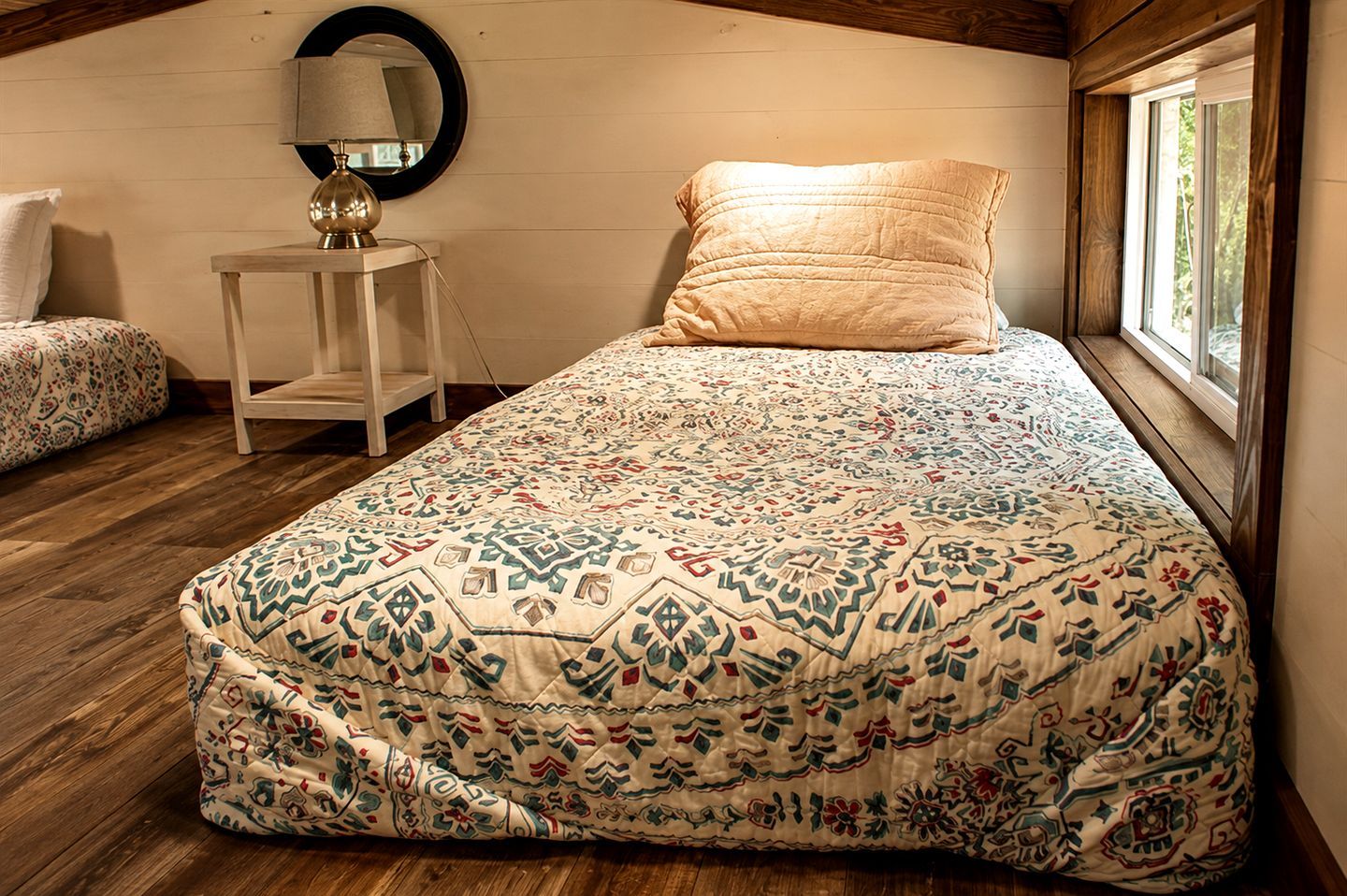 A bedroom with a bed, a bedside lamp, and a window.