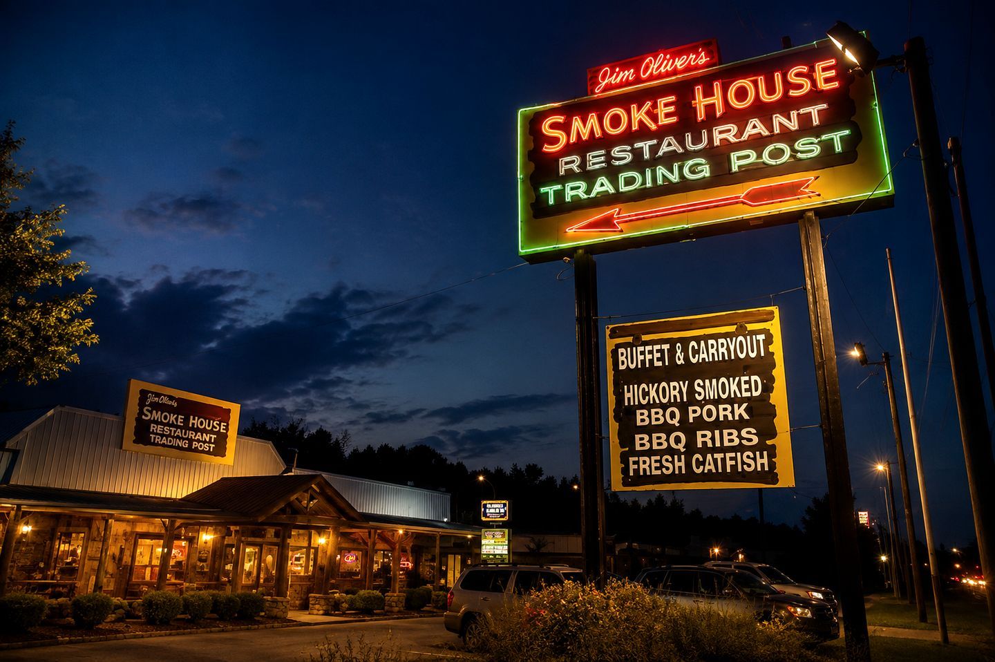 A restaurant with a neon sign indicating it is a smoke house and trading post, featuring a buffet and carryout, hickory smoked BBQ, ribs, and fresh catfish.