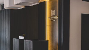 Tumman puuviimeistelyn omaava vastaanottotiski, kultaisella värillä korostettu seinä ja Westin Housei Resort Kolobrzeg -hotellin logo.