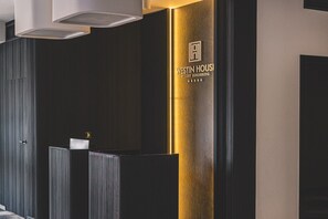 Eine Rezeption mit dunkler Holzvertäfelung, einer Wand mit goldfarbenen Akzenten und dem Logo von Westin Housei Resort Kolobrzeg.