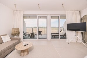 Ein modernes Wohnzimmer mit einer Couch, einem Couchtisch und einem Fernseher auf einem Stativ.