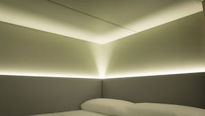 A modern hotel room with a neatly made bed, a flat-screen TV, and a built-in shelf. - Hostel Superlativo Vialia I (Málaga)