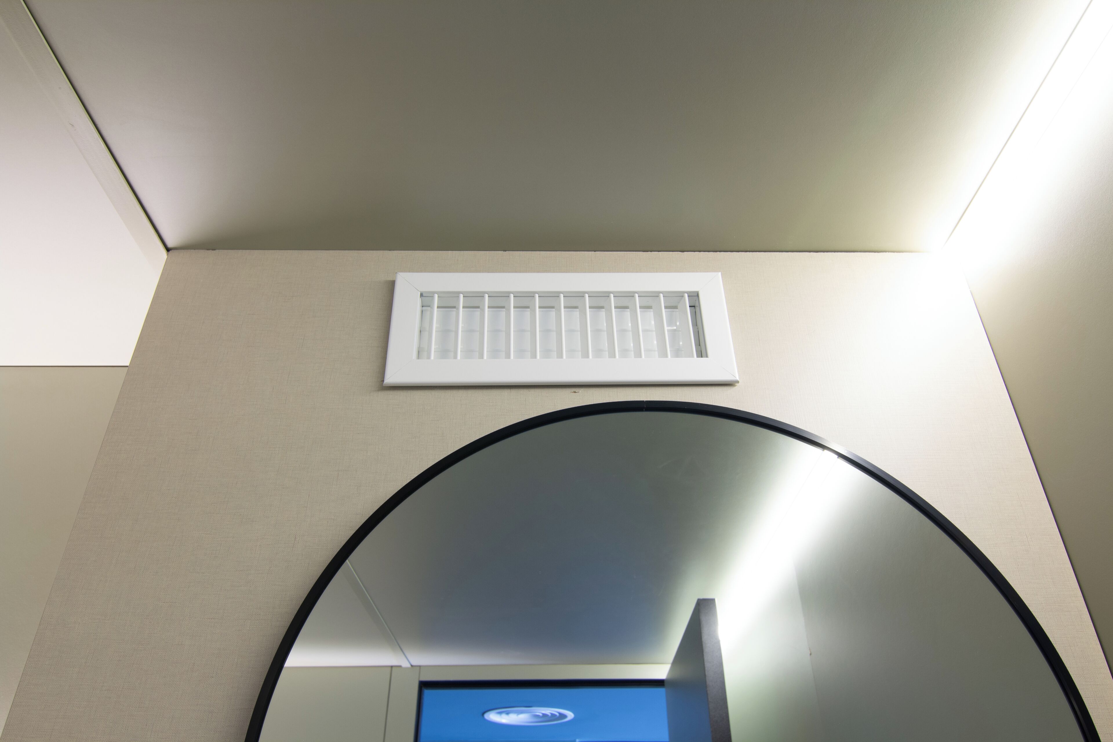 Techo con una rejilla de ventilación y un espejo circular.