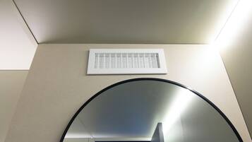 Techo con una rejilla de ventilación y un espejo circular.