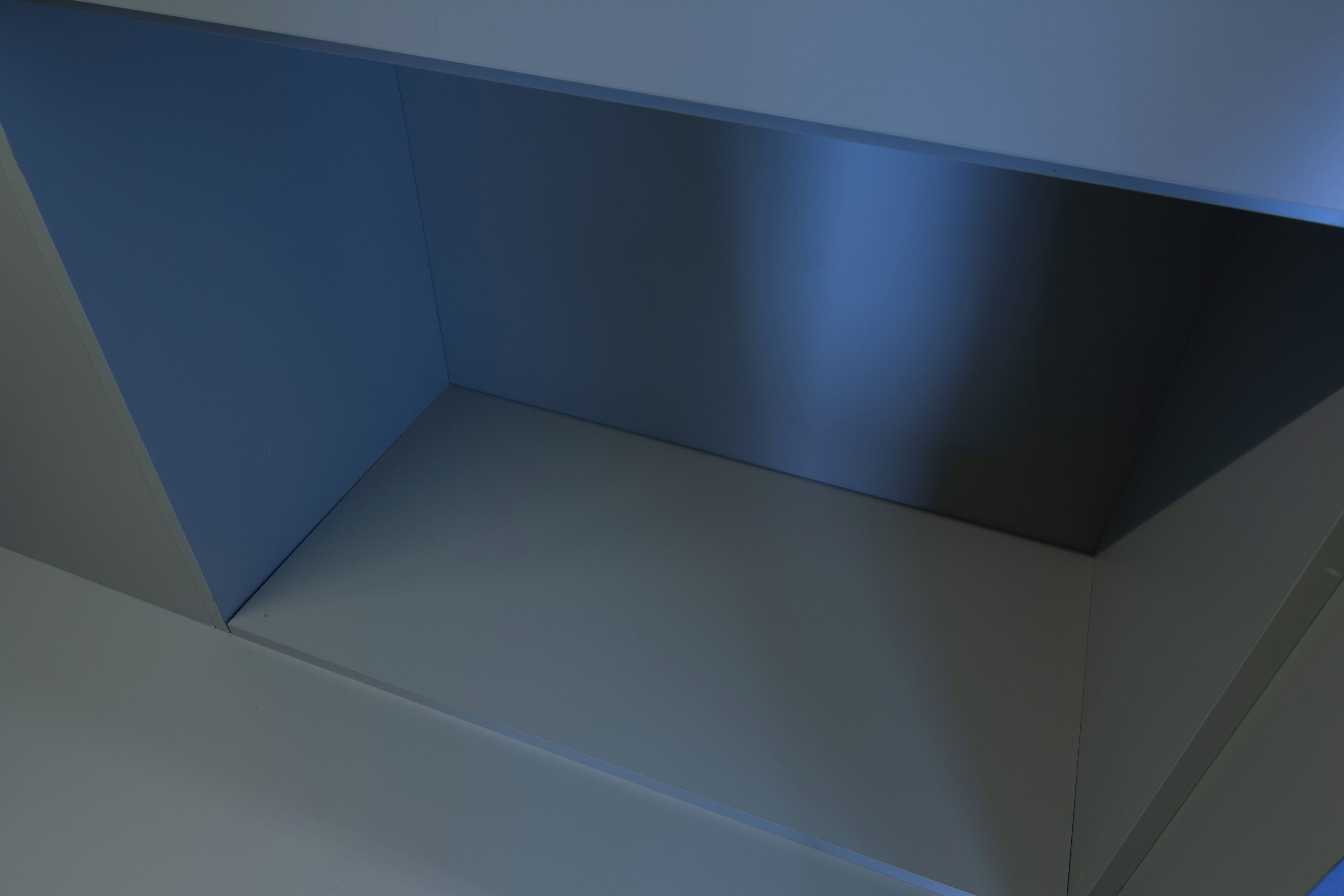 A room with a blue wall, a grey floor, and a white ceiling.