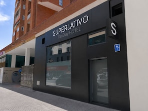 Ett hotell som heter ”Superlativo FlexStay Hotel” med en modern fasad, stora fönster och ett tydligt avgränsat parkeringsområde.