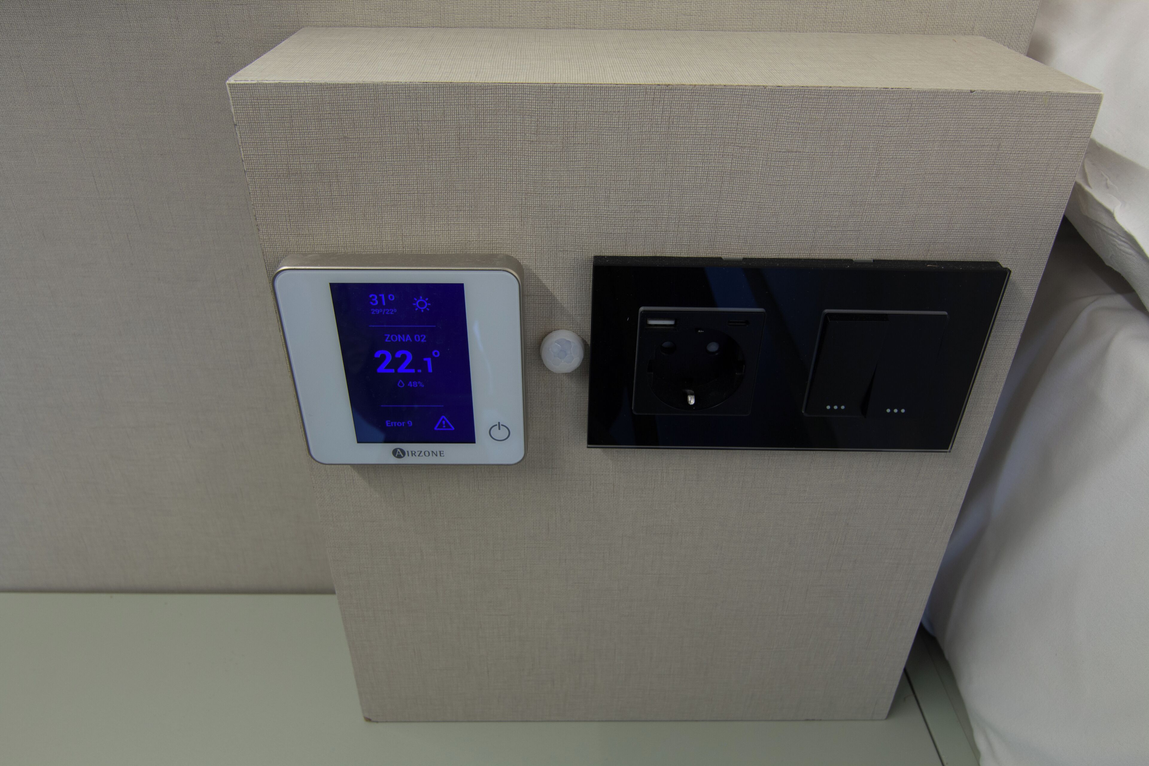 Een thermostaat en bedieningspaneel op een muur, met een temperatuur van 22,1 graden Celsius.