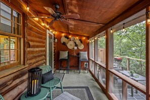 A log cabin interior with a ceiling fan, string lights, and a view of the outdoors. - Romantic and Secluded Log Cabin with Private Hot Tub in Eureka Springs, Arkansas (Eureka Springs)