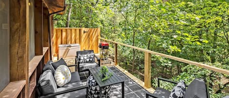Une terrasse extérieure avec un canapé, des chaises, une table et un barbecue.