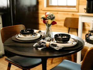 A dining table with plates, bowls, and a vase of flowers. - Romantic and Secluded Log Cabin with Private Hot Tub in Eureka Springs, Arkansas (Eureka Springs)