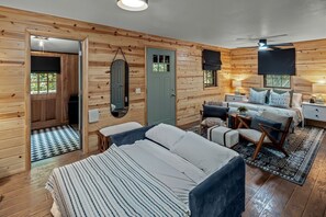 A log cabin-style bedroom with a bed, seating area, and a mirror. - Romantic and Secluded Log Cabin with Private Hot Tub in Eureka Springs, Arkansas (Eureka Springs)