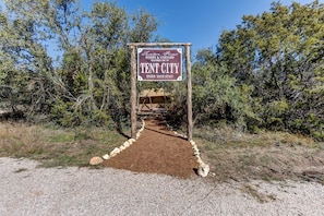 A sign for Tent City, a winery and vineyard, with a dirt path leading to a tent structure.
