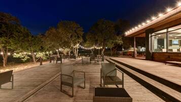 An outdoor patio area with seating, string lights, and a building with large windows.