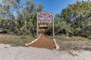 A sign for Tent City, a winery and vineyard, with a dirt path leading to a tent structure.