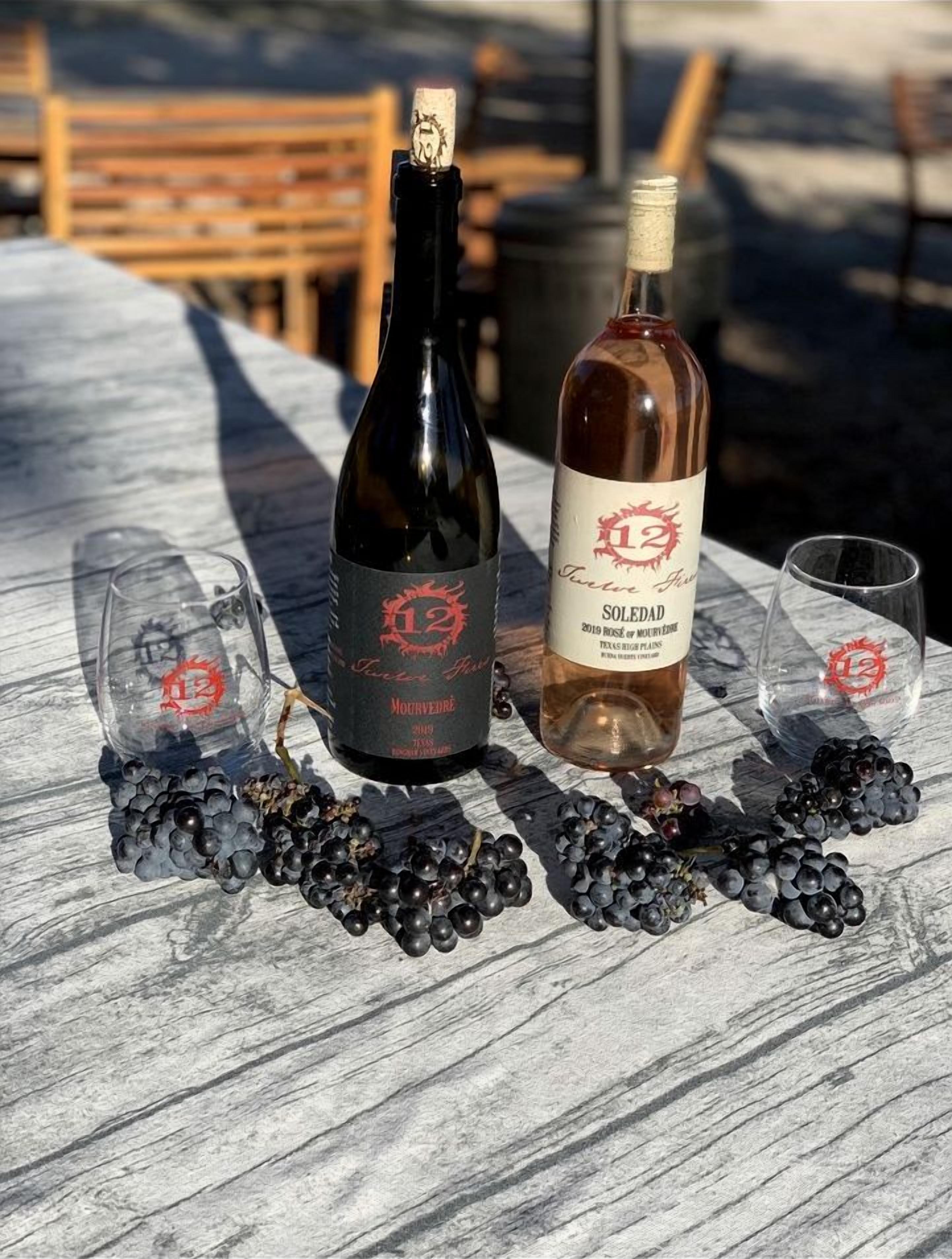 Une table avec deux bouteilles de vin et deux verres, entourée de raisins.