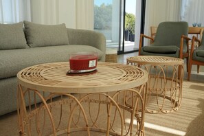 Ein Wohnzimmer mit einer Couch, zwei Korbstühlen und Blick durch eine Glastür.