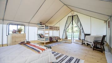 A tented accommodation with a bunk bed, a desk, and a dining area.