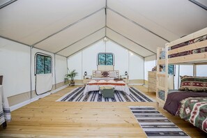 Una habitación con tienda de campaña, cama, cómoda, ventana y planta.