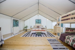 A tented room with a bed, a dresser, a window, and a plant.
