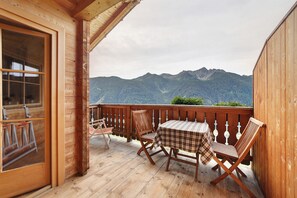 A wooden deck with a table and chairs, a view of mountains, and a wooden building. - Apartment "Hochwart" at Innerdurachhof with Lake and Mountain Views (Durago di Dentro)
