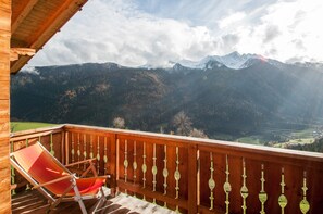 A wooden balcony with a red chair, overlooking a mountainous landscape with a clear sky. - Apartment 'Innerdurachhof Hochwart' with Lake View, Shared Terrace and Wi-Fi (Durago di Dentro)