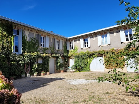 A building with a gravel courtyard, white shutters, and ivy-covered walls.. "L'Annexe de Camillac - Chambres d'hôtes Côtes Bourg Gironde" on the Vélodyssée