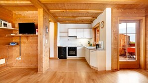 Un interno in legno con angolo cottura, zona pranzo e televisione.
