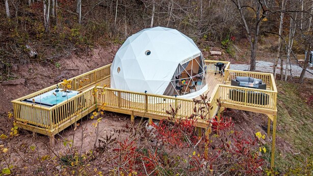 Estructura geodésica tipo cúpula con terraza y zona de estar al aire libre.