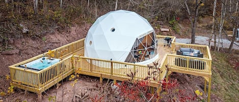 Une structure en forme de dôme géodésique dotée d’une terrasse et d’un espace de détente extérieur.