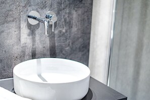 A bathroom with a white sink, a chrome faucet, and a textured wall.