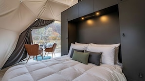 Un dormitorio con una cama grande, cabecera y vistas por una ventana.
