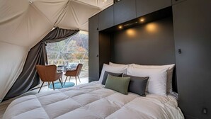 Un dormitorio con una cama grande, cabecera y vistas por una ventana.