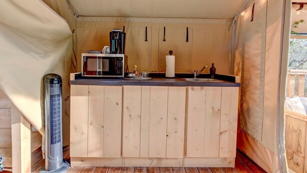 A compact kitchen with a microwave, kettle, and sink.