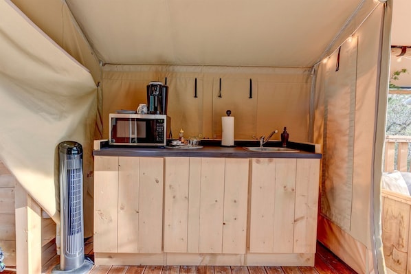 A compact kitchen with a microwave, kettle, and sink.